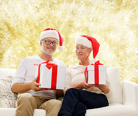 Image showing happy senior couple in santa hats with gift boxes