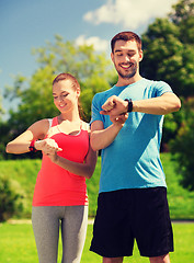 Image showing smiling people with heart rate watches outdoors