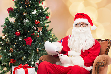 Image showing man in costume of santa claus with notepad