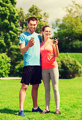 Image showing two smiling people with smartphones outdoors