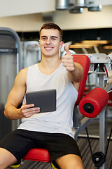 Image showing smiling young man with tablet pc computer in gym