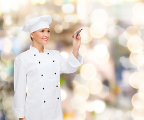 Image showing smiling female chef writing something on air