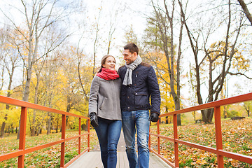 Image showing smiling couple hugging on bridge in autumn park