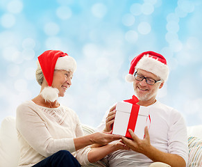 Image showing happy senior couple in santa hats with gift box