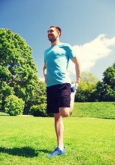 Image showing smiling man stretching outdoors