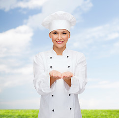 Image showing smiling female chef holding something on hands