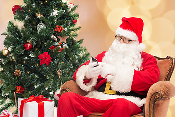 Image showing santa claus with smartphone and christmas tree