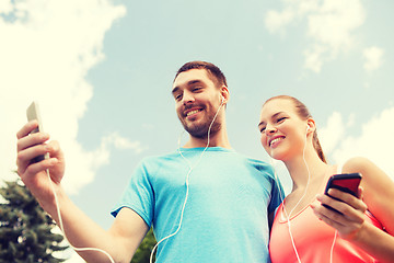 Image showing two smiling people with smartphones outdoors