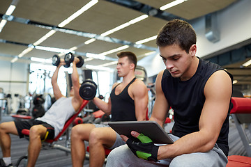 Image showing group of men with tablet pc and dumbbells in gym