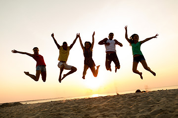 Image showing smiling friends dancing and jumping on beach