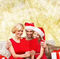 Image showing happy family in santa hats with greeting card