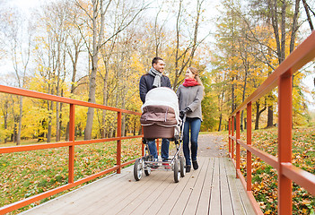 Image showing smiling couple with baby pram in autumn park