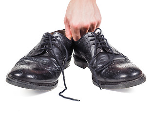 Image showing Male hands holding up a pair of worn black leather shoes towards