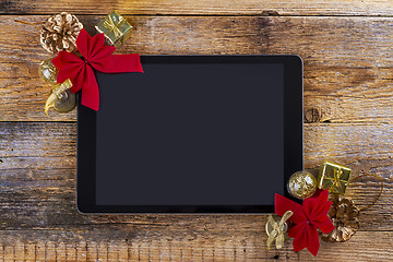 Image showing tablet pc with  christmas decorations on wooden background