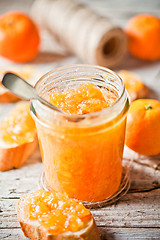 Image showing orange jam in glass jar, tangerines and bread 