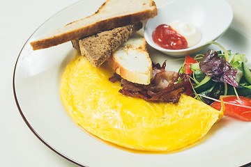 Image showing Omelet with bacon served on white plate, vegetables aside