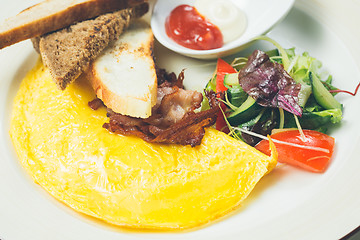 Image showing Omelet with bacon served on white plate, vegetables aside