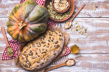 Image showing Newly baked white bread with seeds and pumpkin on wood