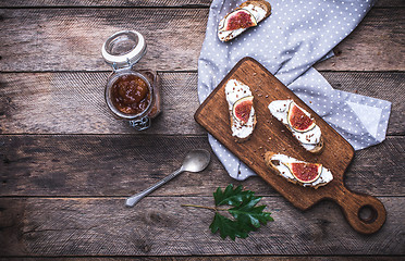 Image showing Sliced figs, jam and Bruschetta on choppingboard in rustic style