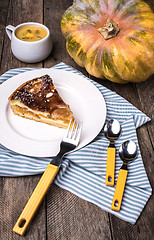 Image showing piece of pie with pumpkin and cream soup on table in Rustic styl