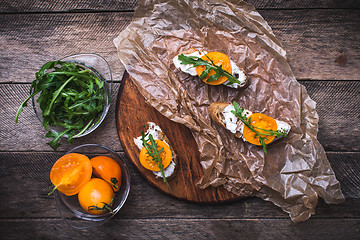 Image showing Bruschetta with tomatoes and salad rocket on board in rustic sty