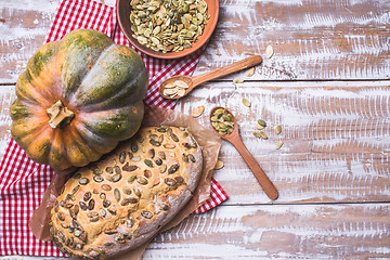 Image showing White bread with pumpkin seeds on wooden table