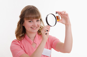 Image showing Pharmacist considers the liquid through a magnifying glass