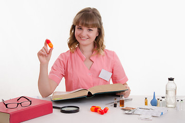 Image showing Pharmacist sitting at table with the pill and reference