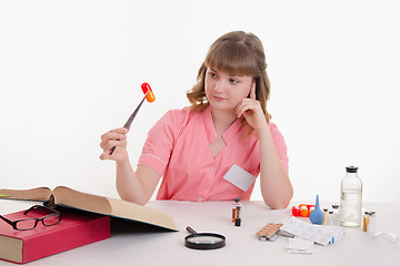 Image showing Pharmacist sitting at a table with tweezers on the pill