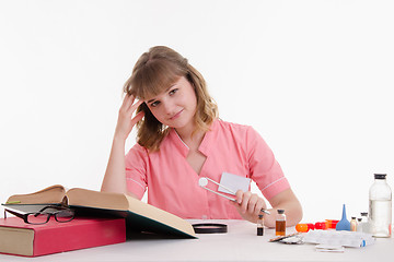 Image showing Student Pharmacist delves into directory, tweezers in hand with a tablet