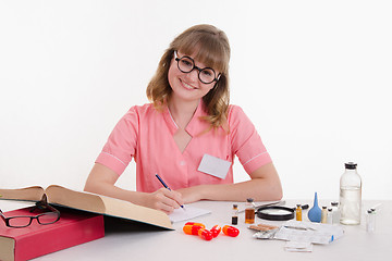 Image showing Pharmacist writing in notebook sitting at a table