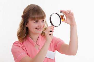 Image showing Pharmacist considers the liquid through a magnifying glass