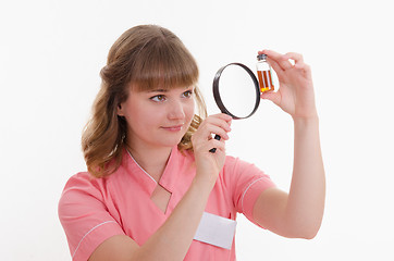 Image showing Pharmacist surprise considering liquid through a magnifying glass