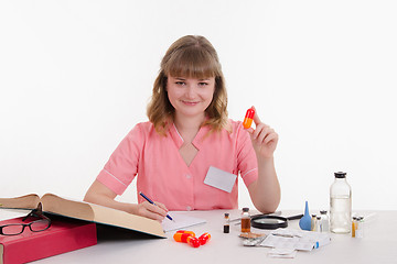 Image showing Pharmacist writing in a notebook composition pills