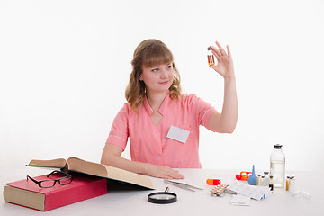 Image showing Pharmacist looking liquid in vial, sitting at table