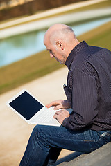 Image showing Man sitting on a bench using a laptop