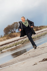 Image showing Happy senior woman frolicking on the beach