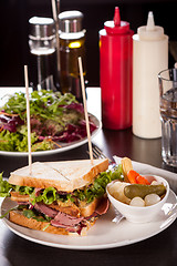 Image showing Delicious pastrami club sandwich and pickles