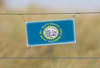 Image showing Border fence - Old plastic sign with a flag