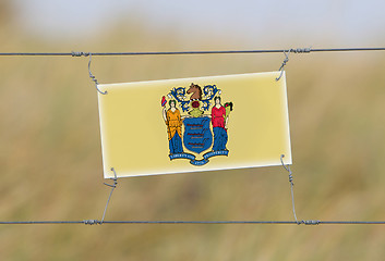 Image showing Border fence - Old plastic sign with a flag