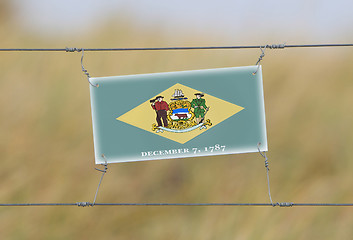 Image showing Border fence - Old plastic sign with a flag