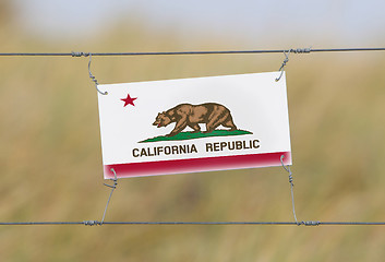 Image showing Border fence - Old plastic sign with a flag