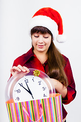 Image showing blue-eyed beautiful girl in santa hat with clock