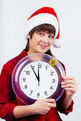 Image showing blue-eyed beautiful girl in santa hat with clock