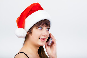 Image showing blue-eyed beautiful girl in santa hat with phone