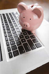 Image showing Piggy Bank Resting on Laptop Computer