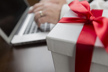 Image showing White Gift Box with Red Bow Near Man using Laptop