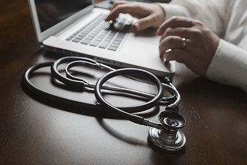 Image showing Stethoscope near Man Typing on Laptop Computer