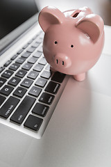 Image showing Piggy Bank Resting on Laptop Computer