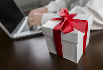 Image showing White Gift Box with Red Bow Near Man using Laptop